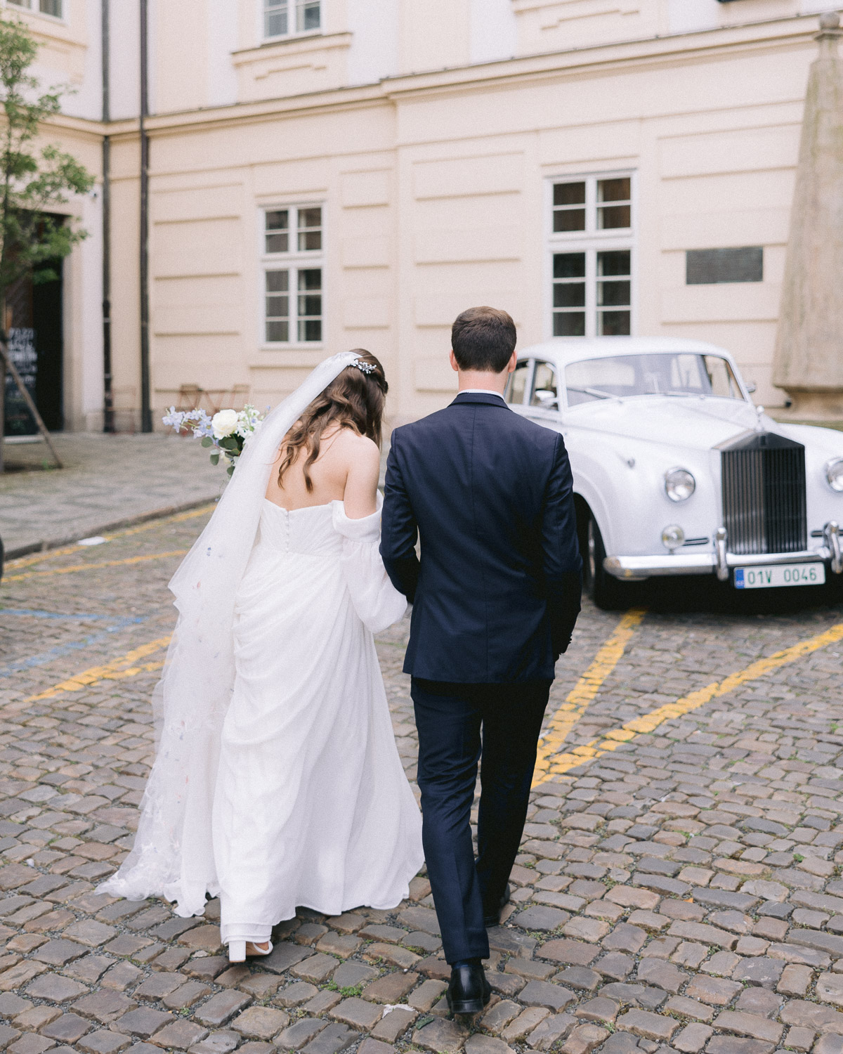 Bride and groom walking to a vintage Rolls-Royce in Malá Strana