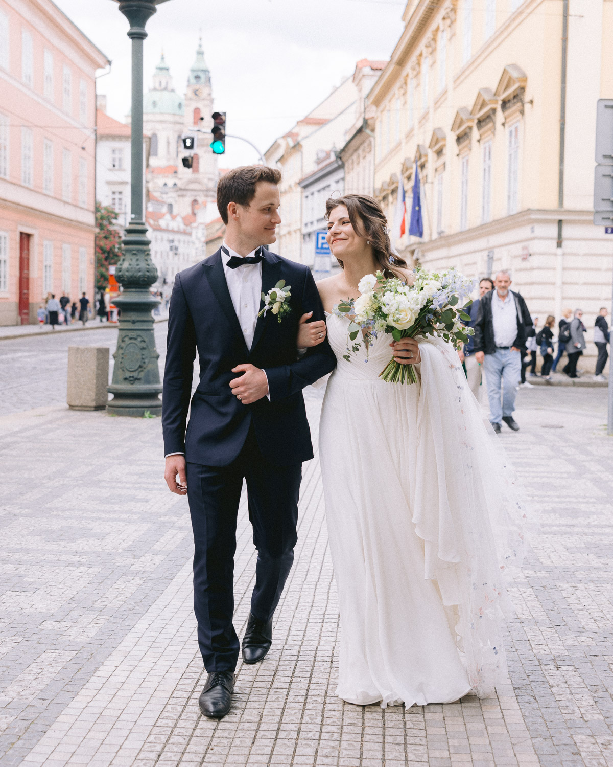 Bride and groom walking arm in arm through Malá Strana