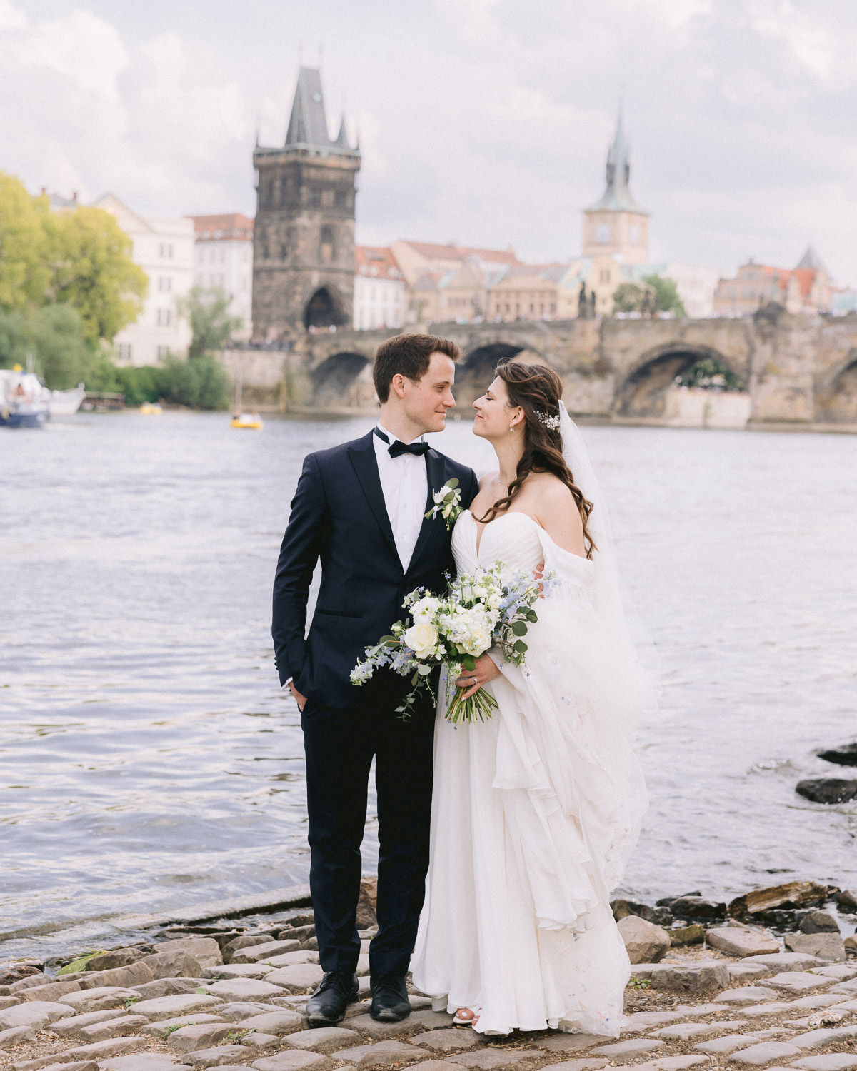 Bride and groom by the Vltava with Charles Bridge behind them