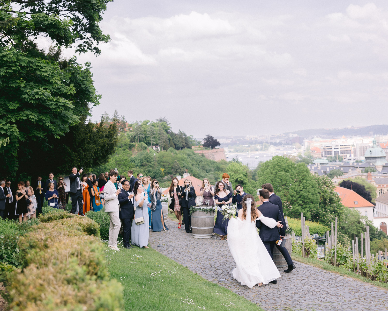 Wedding couple and guests on the Villa Richter terrace above the vineyard, with Prague behind them