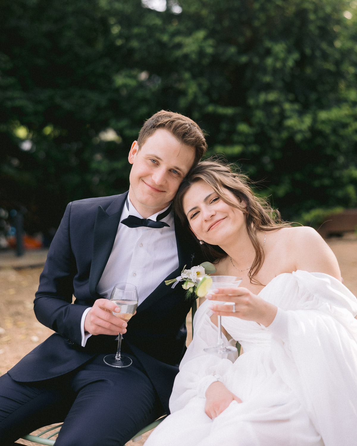 Bride and groom smiling with glasses of wine in the garden at Villa Richter