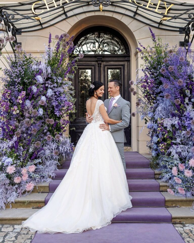 Bride and groom at the Château Mcely entrance framed by lavender flowers