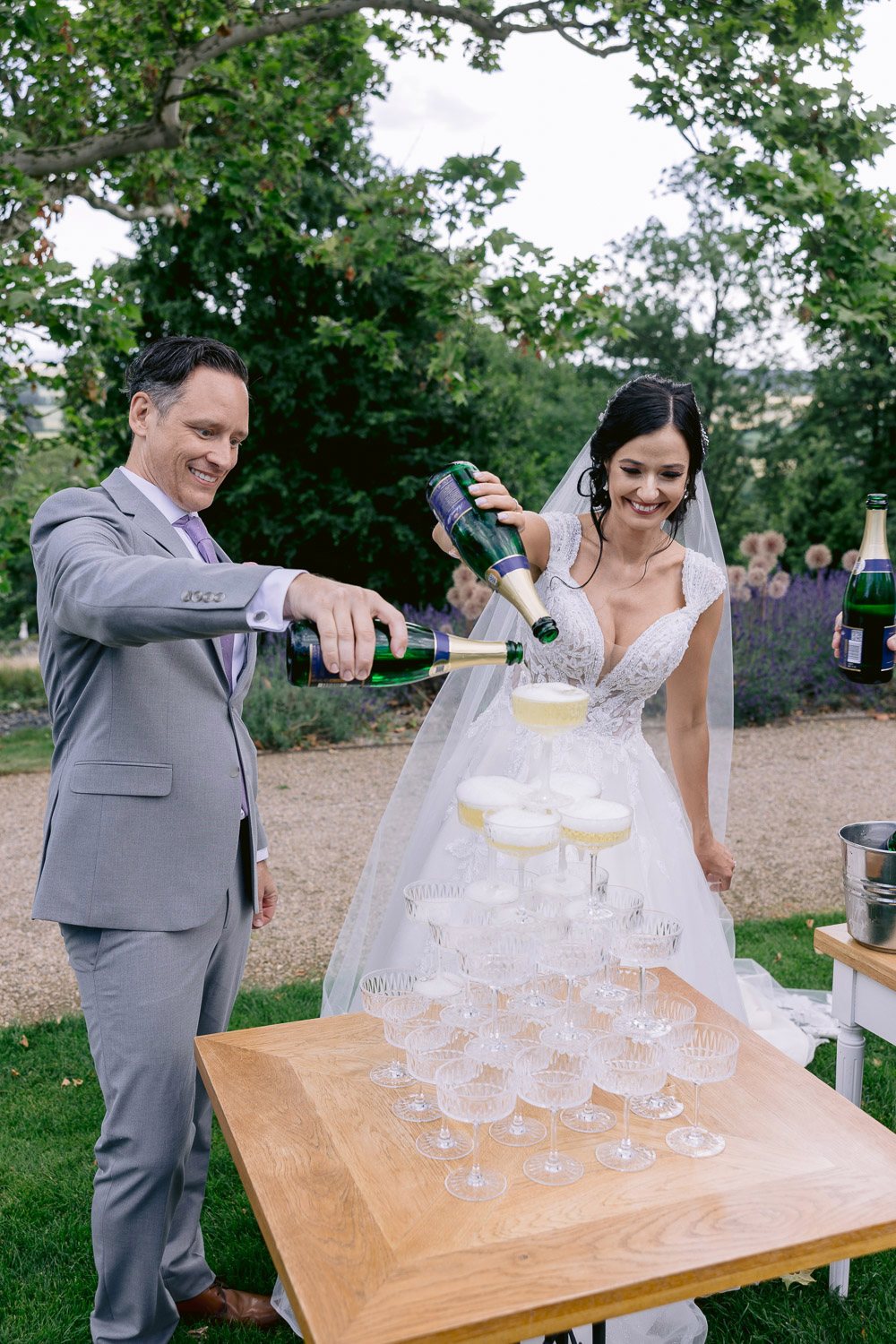 Chateau Mcely Champagne Tower Groom pouring a champagne tower in the garden