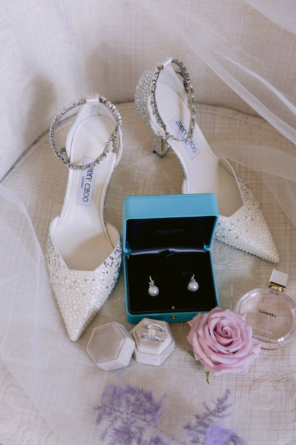 Chateau Mcely Wedding Bridal Shoes Earrings Bridal shoes and earrings laid out with lilac flowers