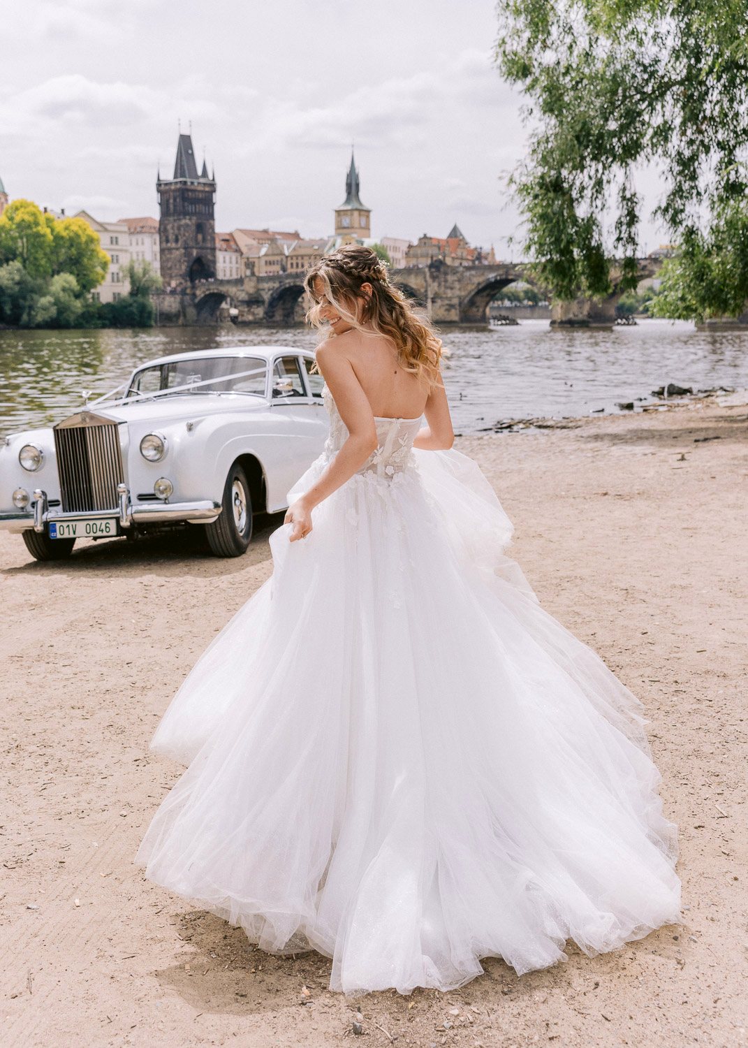Lobkowicz Palace Elopement Bride Dress Riverbank Bride walking on the riverbank with Charles Bridge behind