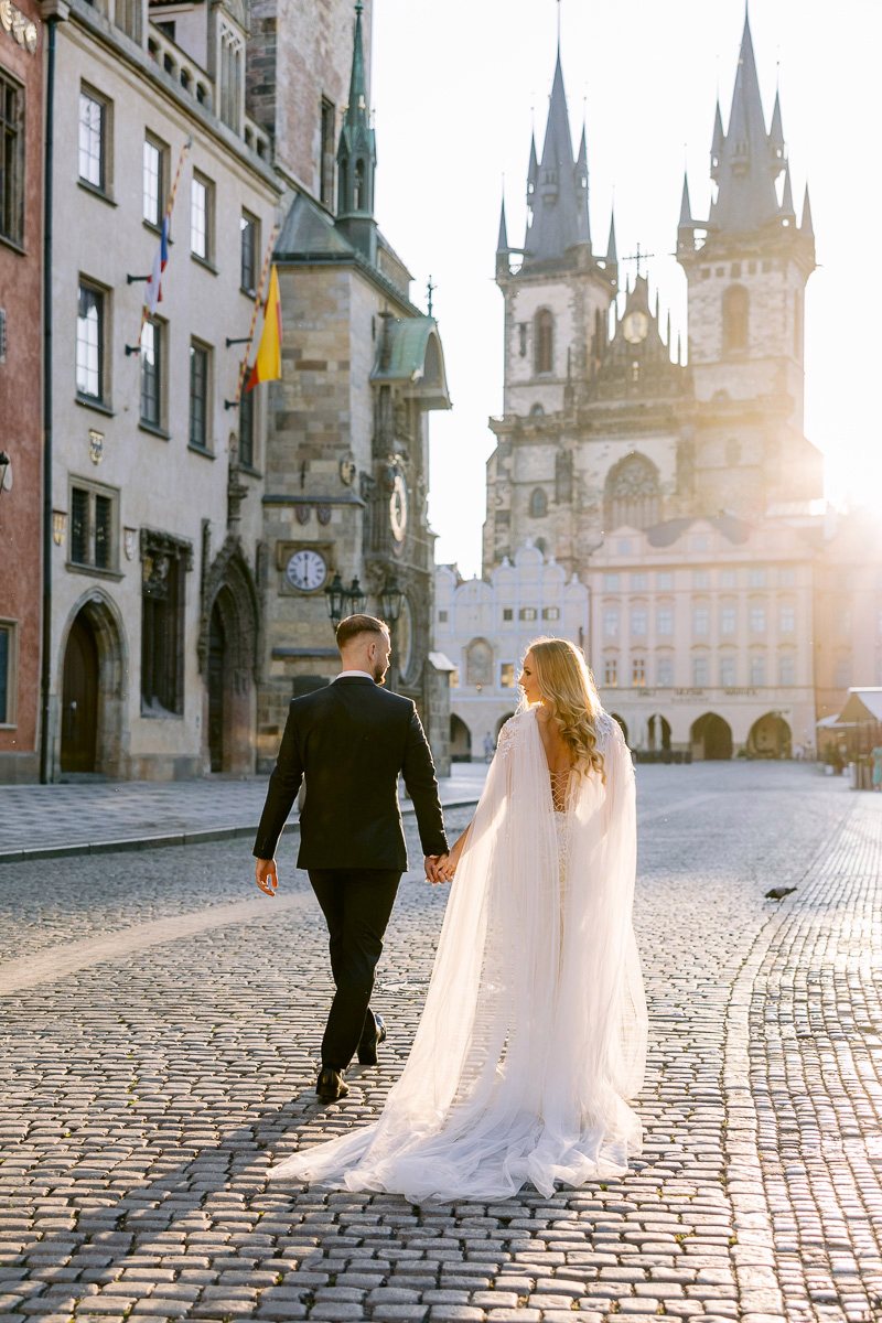 Old-town-square-wedding-couple-walking Couple walking across Old Town Square in Prague at sunrise