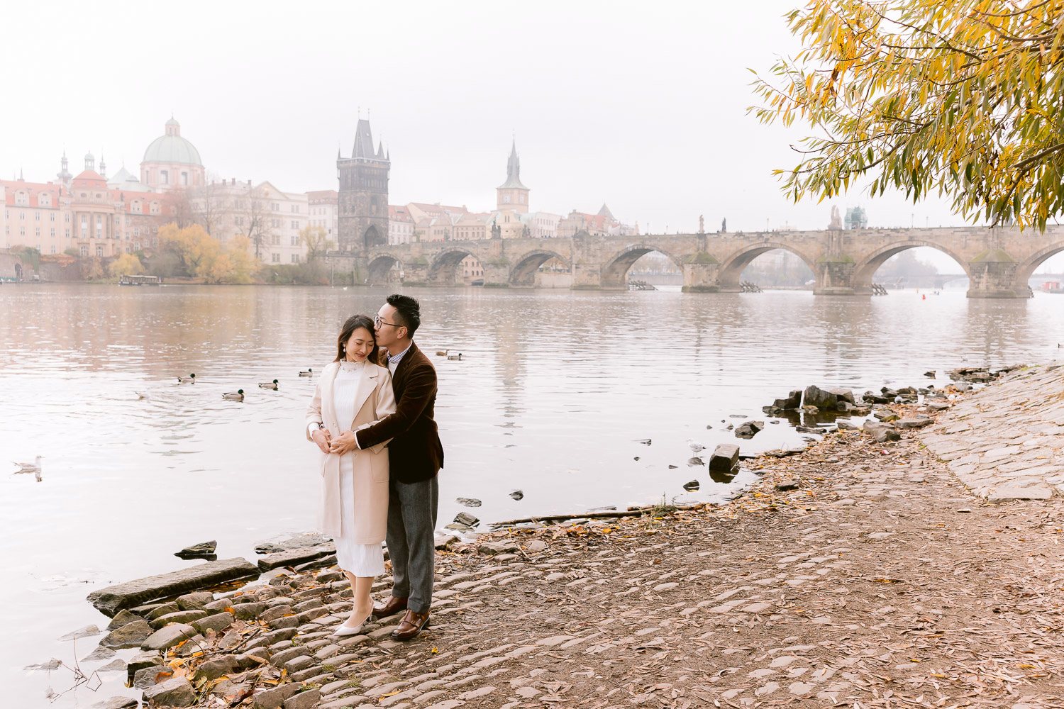 Couple on the riverbank with Charles Bridge behind