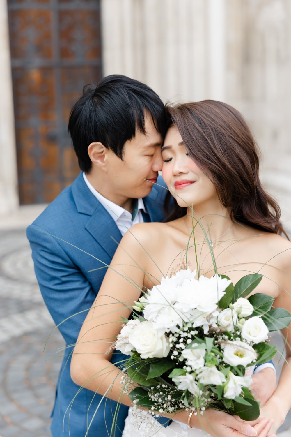 Review Jeanne Budapest Pre Wedding 3 Couple embracing with a white bouquet during their Budapest pre-wedding shoot