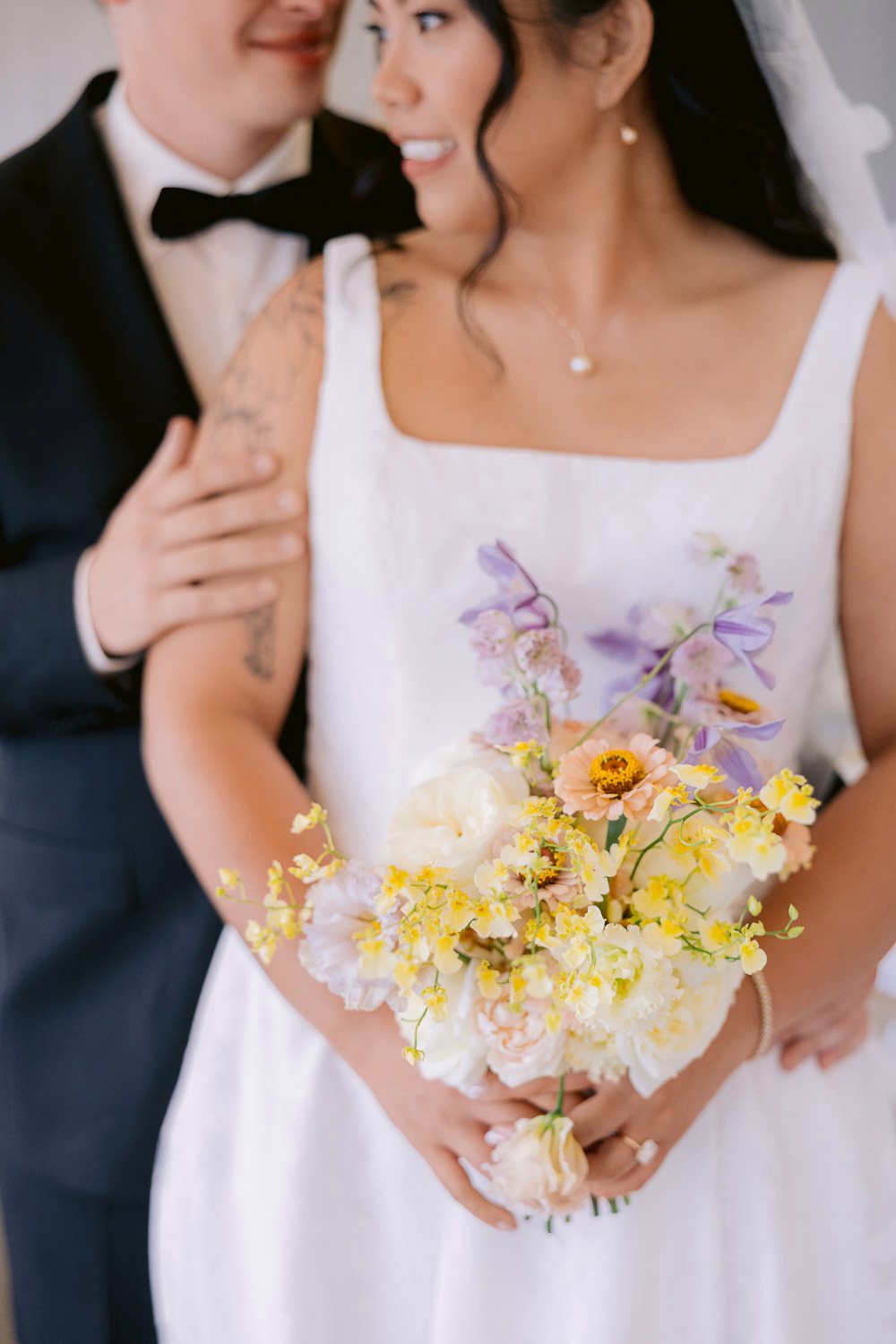 Villa Richter Bride Bouquet Yellow Lilac Groom holding the bride, her bouquet of yellow and lilac flowers in focus