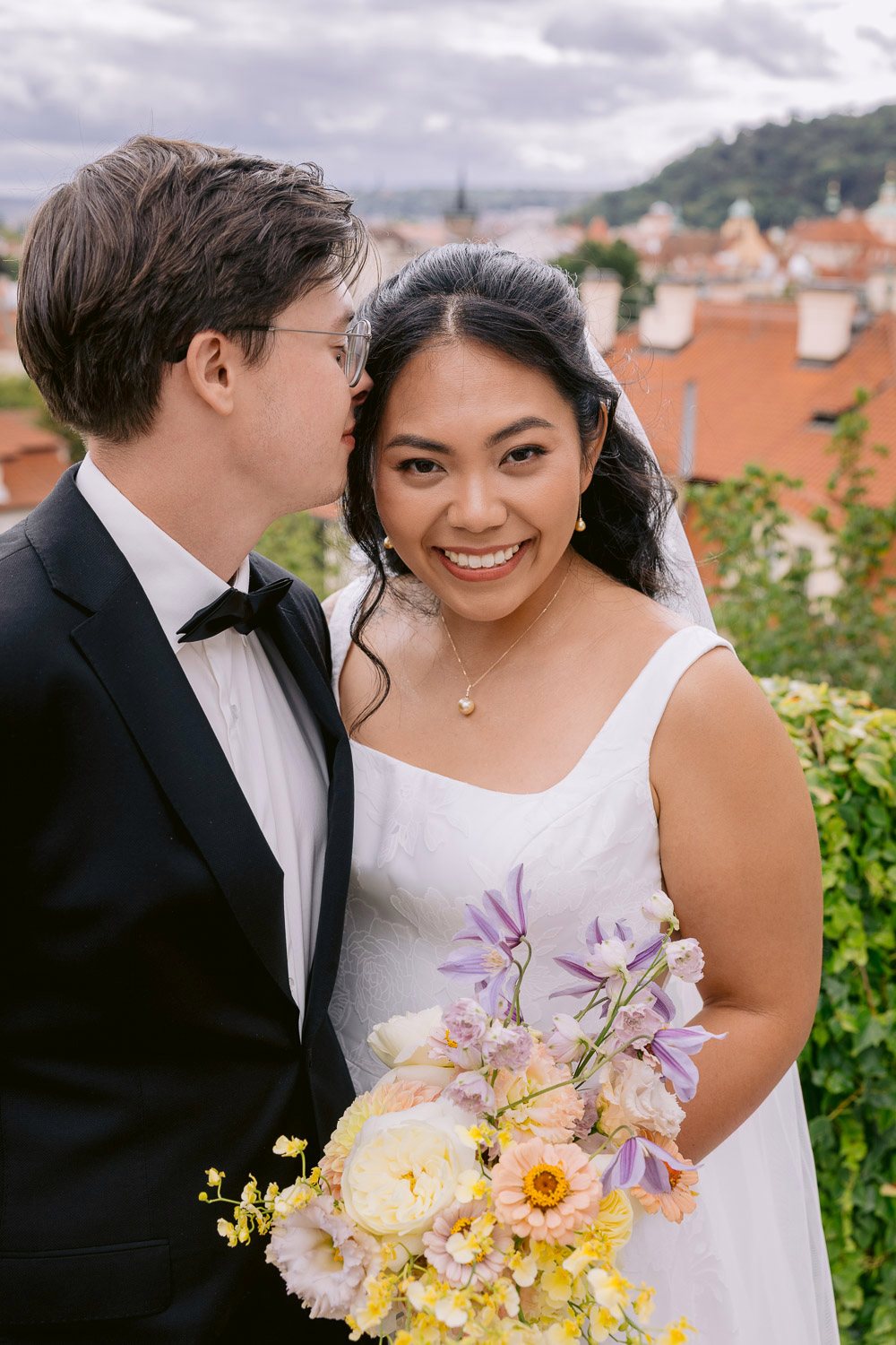 Villa Richter Couple Portrait Bouquet Prague Groom kissing the bride with Malá Strana behind them